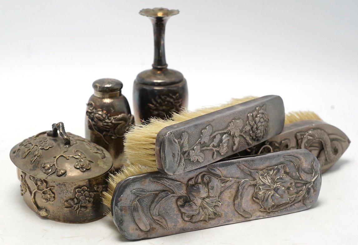 An early 20th century Japanese oval white metal box and associated? cover, 10.2cm, together with a similar posy vase, jar without cover and three mounted clothes brushes. Condition - fair to poor